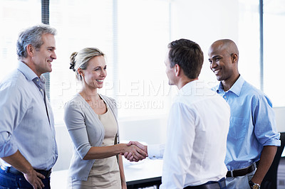 Buy stock photo Shot of a diverse group of coworkers shaking hands and talking in an office