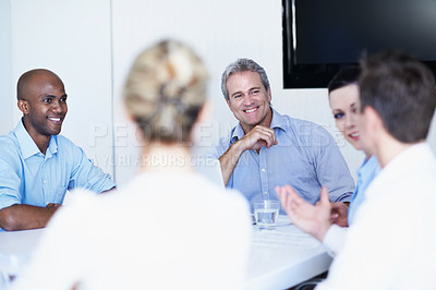 Buy stock photo Shot of a group of coworkers talking while sitting around a boardroom table