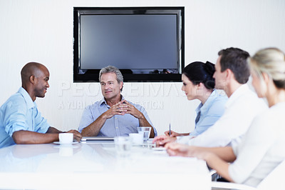 Buy stock photo Shot of a group of coworkers having a meeting while sitting around a boardroom table
