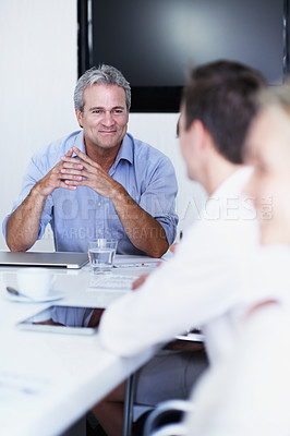 Buy stock photo Shot of a group of coworkers having a meeting while sitting around a boardroom table
