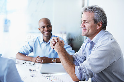 Buy stock photo Shot of a diverse group of coworkers having a meeting while sitting around a boardroom table