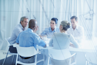 Buy stock photo Through the window shot of a group of businesspeople having a meeting in a boardroom