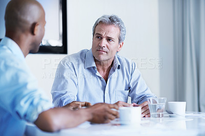 Buy stock photo Shot of two businessman talking while sitting at a boardroom table