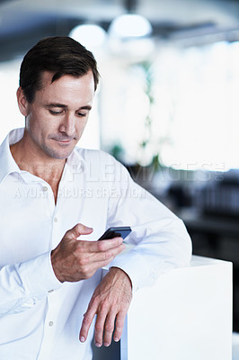 Buy stock photo Shot of a man using a cellphone while standing in an office