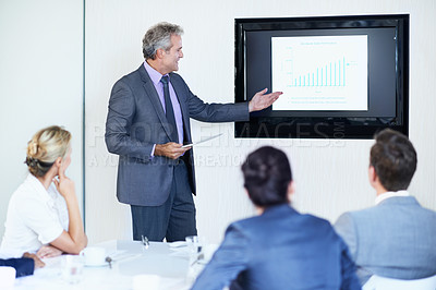 Buy stock photo Shot of a mature businessman giving a video presentation to colleagues in a boardroom