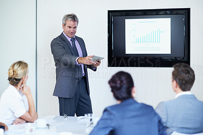 Buy stock photo Shot of a mature businessman giving a video presentation to colleagues in a boardroom