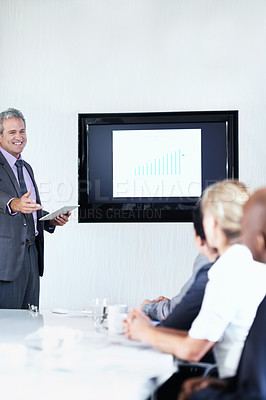Buy stock photo Shot of a mature businessman giving a video presentation to colleagues in a boardroom
