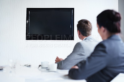 Buy stock photo Shot of a group of businesspeople sitting around a boardroom table looking at a blank monitor