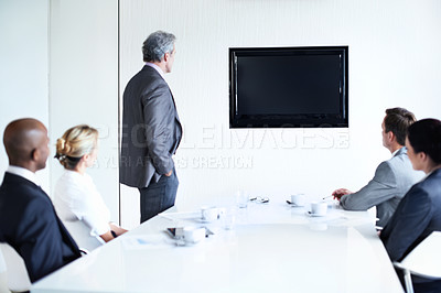 Buy stock photo Shot of a group of businesspeople in a boardroom looking at a blank monitor