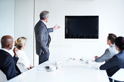 Buy stock photo Shot of a group of businesspeople in a boardroom looking at a blank monitor