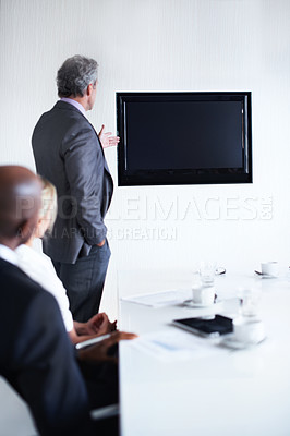 Buy stock photo Rearview shot of a group of businesspeople in a boardroom looking at a blank monitor