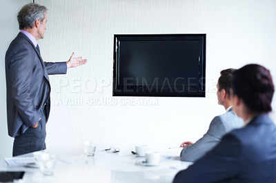 Buy stock photo Rearview shot of a group of businesspeople in a boardroom looking at a blank monitor