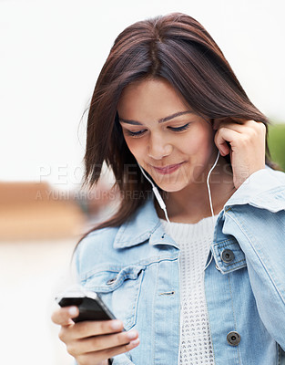 Buy stock photo Attractive young teen smiling and listening to music on her smartphone