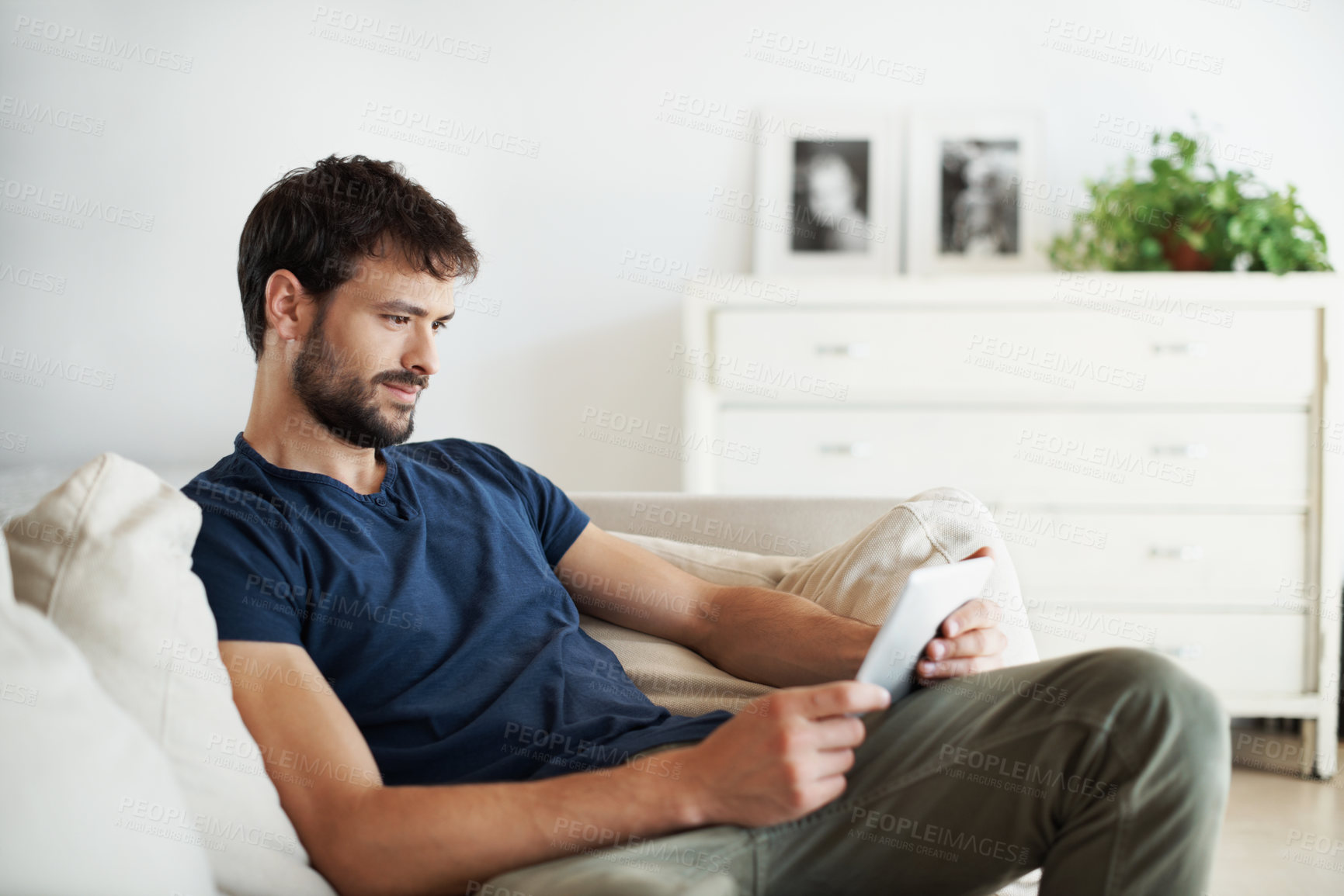 Buy stock photo Tablet, relax and reading with man on sofa in home for streaming service, movie search or media app. Online film platform, subscription and chill with person in house for connection and entertainment