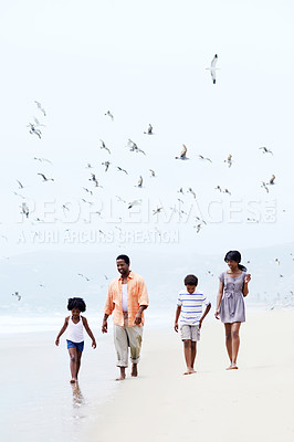 Buy stock photo A happy Afircan-American family walking on the beach