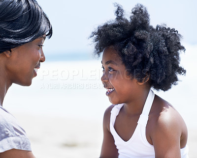 Buy stock photo A young African-American mother sitting with her daughter on the beach