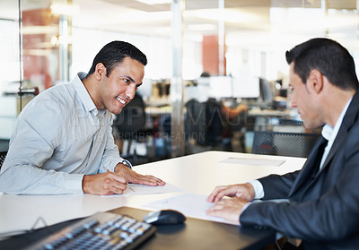 Buy stock photo Two coworkers looking over some paperwork at a desk in the office