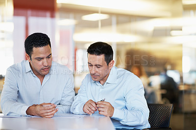 Buy stock photo Two coworkers sitting at a desk and looking over some paperwork