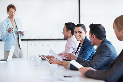 Buy stock photo Portrait of a young businesswoman amongst her coworkers attending staff training in a board room