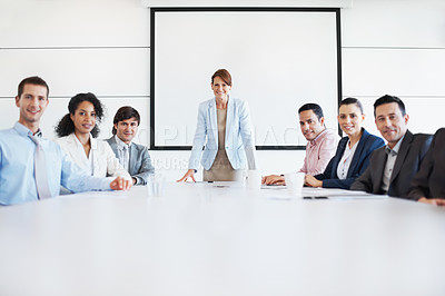 Buy stock photo A group of coworkers sitting at a conference table with a female executive leaning forward