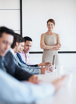 Buy stock photo Portrait of a businesswoman standing in a conference room beside her coworkers with a defocused foreground