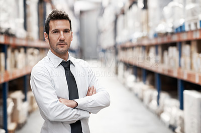 Buy stock photo Handsome warehouse manager standing in a warehouse with his arms folded