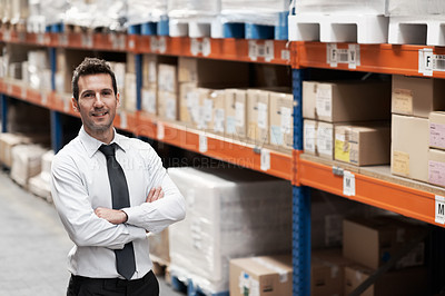 Buy stock photo Handsome warehouse manager standing in a warehouse with his arms folded