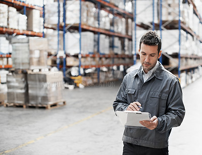 Buy stock photo Handsome warehouse worker doing a stocktake while in a warehouse