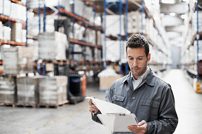 Buy stock photo Handsome warehouse worker doing a stocktake while in a warehouse