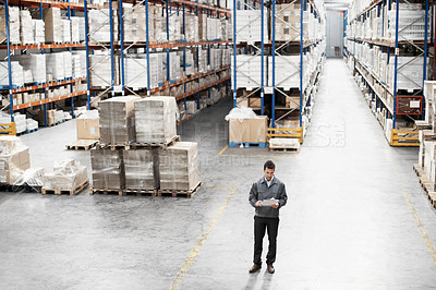 Buy stock photo Handsome warehouse worker doing a stocktake while in a warehouse