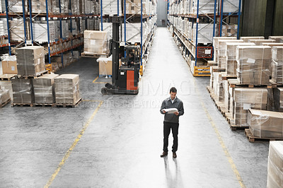Buy stock photo Handsome warehouse worker doing a stocktake while in a warehouse