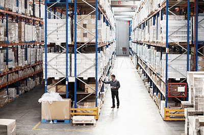 Buy stock photo Handsome warehouse worker doing a stocktake while in a warehouse