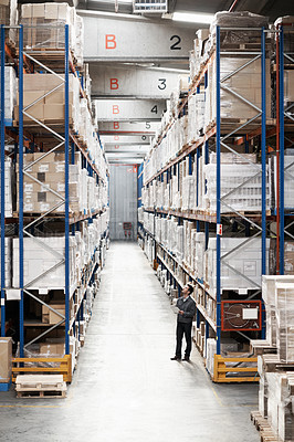 Buy stock photo Handsome warehouse worker doing a stocktake while in a warehouse