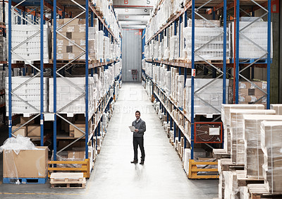 Buy stock photo Handsome warehouse worker doing a stocktake while in a warehouse