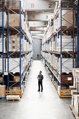 Buy stock photo Handsome warehouse worker doing a stocktake while in a warehouse