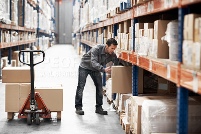 Buy stock photo A young man using a pallet truck to move boxes in a warehouse