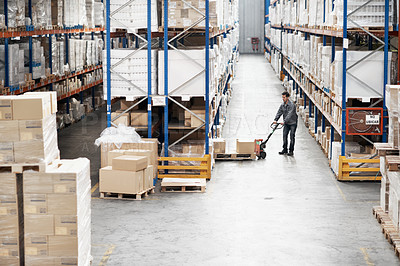 Buy stock photo A young man moving boxes in a storehouse using a pallet truck