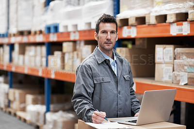 Buy stock photo Portrait of a young man working on his notebook while working in a warehouse