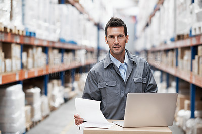 Buy stock photo Portrait of a young man working on his laptop while sitting in a storehouse