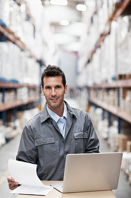 Buy stock photo Portrait of a young man using his laptop while sitting in a storehouse