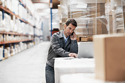 Buy stock photo A young man in a warehouse placing orders on his mobile phone and recording them on his laptop