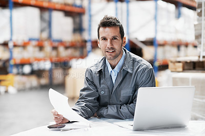 Buy stock photo Portrait of a young man using his notebook while sitting in a warehouse