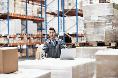 Buy stock photo Portrait of a young man working on his notebook while sitting in a storehouse