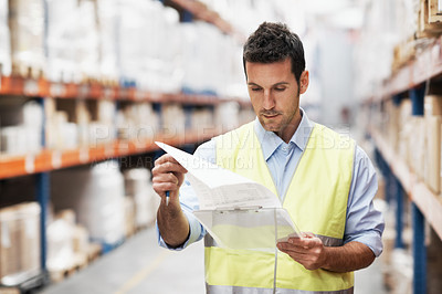 Buy stock photo A young man doing a stock check in a storehouse