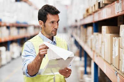Buy stock photo A young man taking stock in a storehouse