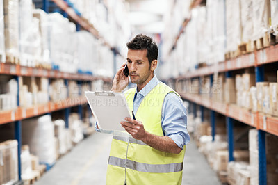 Buy stock photo A young man in a warehouse taking orders on his mobile phone