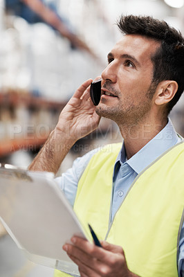 Buy stock photo A young man in a storehouse taking orders on his mobile phone