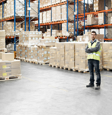 Buy stock photo Portrait of a young man standing with his arms folded in a storehouse