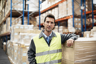 Buy stock photo Portrait of a young man leaning on some boxes in a storehouse