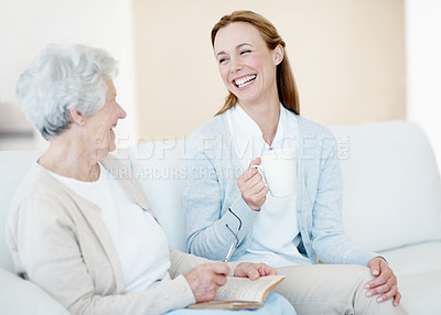 Buy stock photo Bonding, daughter or old woman on couch with laugh, chat or happiness in home with coffee. Smile, people and senior parent with book in lounge, connection or joke with love in retirement together